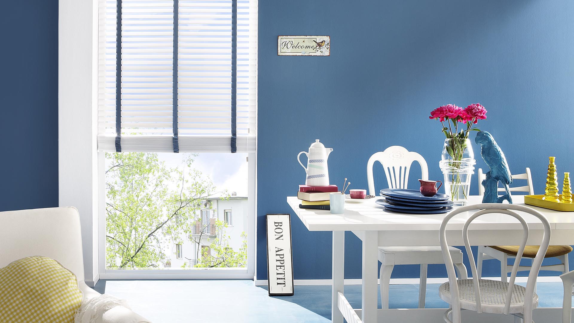 Weiße Jalousien mit einem blauen Leiterband an einem Esszimmerfenster.