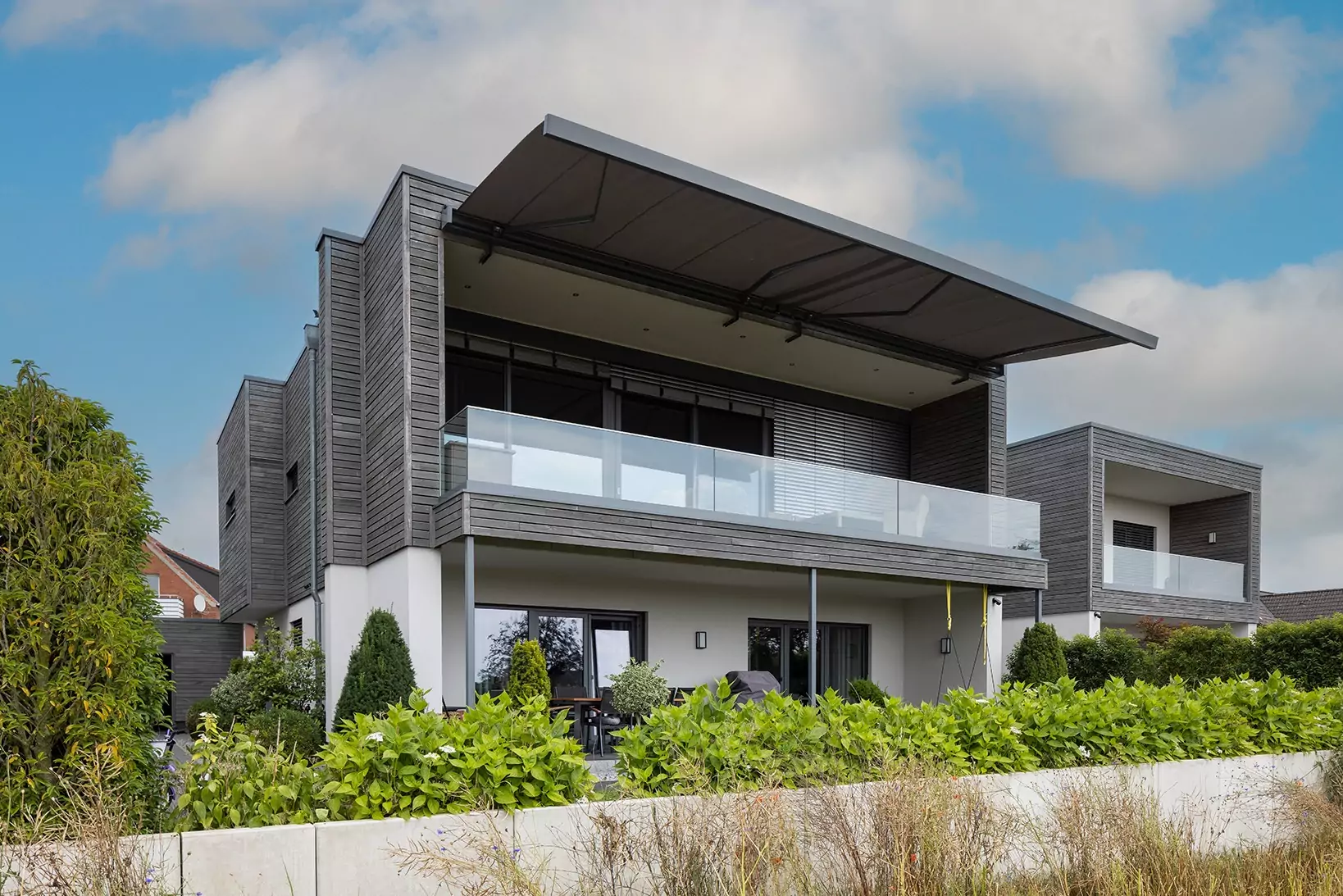 Gekoppelte Kassettenmarkise an einem Neubau – eleganter Sonnenschutz von DIX GmbH für große Terrassen.