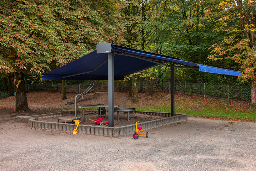WAREMA Markisenfreigestell mit 2x offener Gelenkarm-Markise 530 über einem Wasser- & Sandspielplatz an einer Kindertagesstätte in Mülheim an der Ruhr.